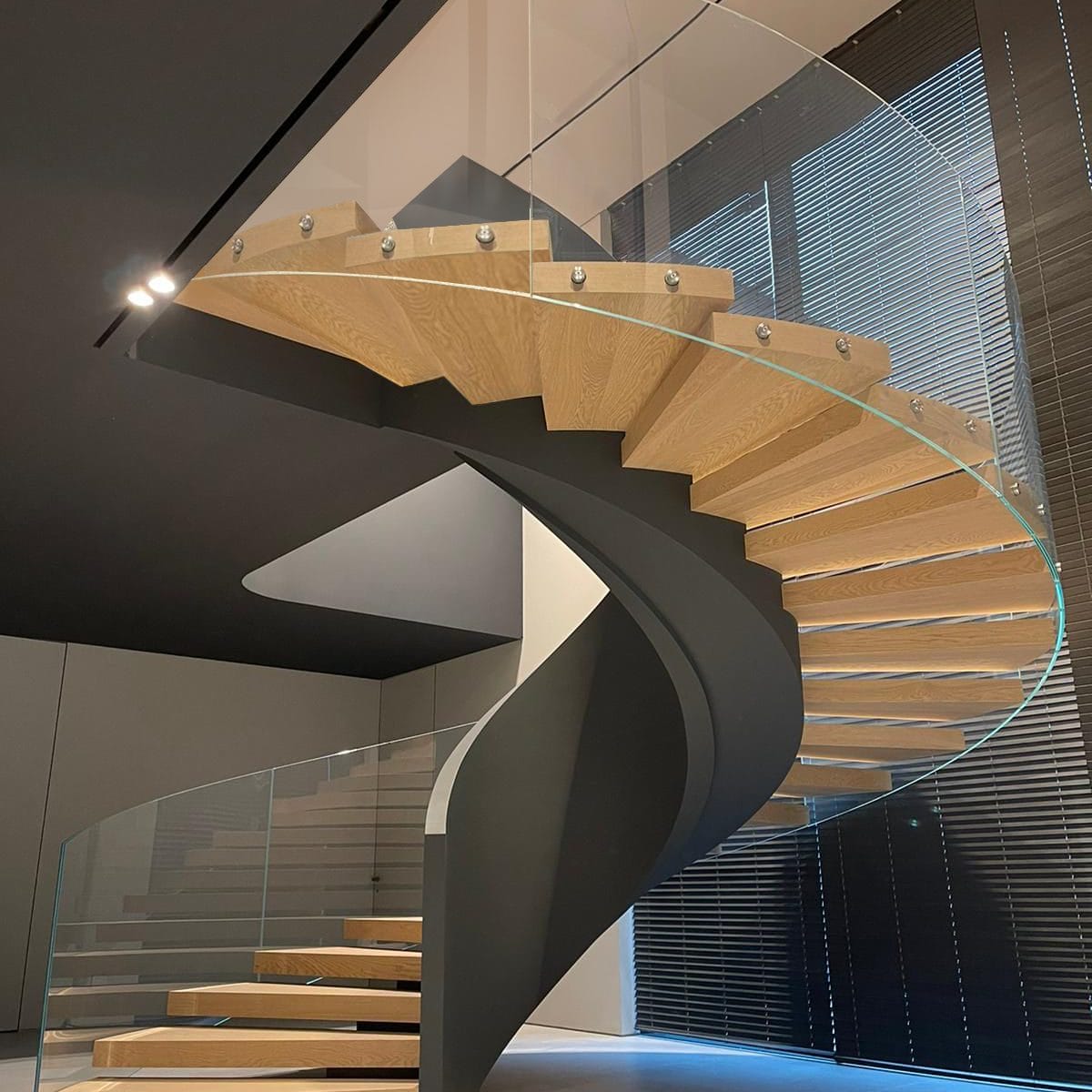 Discover our modern helical staircase with cherry wood stairs and glass panel balustrades, showcasing V.P Stairs Ltd's expertise and craftsmanship in the UK.