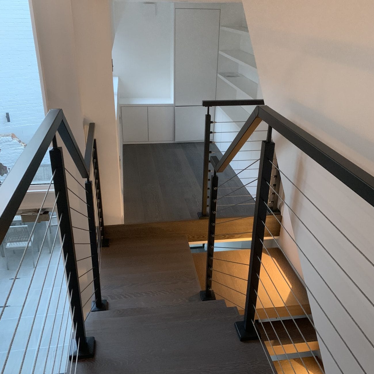 Elegant spinal staircase with cable balustrades, meticulously crafted to complement the modern space it inhabits with a touch of luxury.