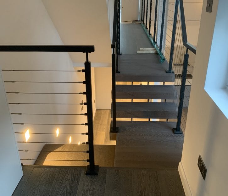 Sophisticated spinal staircase with cable balustrades, flawlessly incorporated into a modern setting to elevate the space with luxurious design elements.