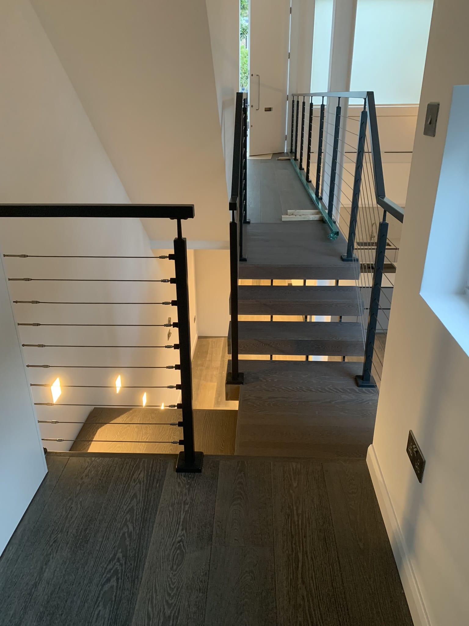 Sophisticated spinal staircase with cable balustrades, flawlessly incorporated into a modern setting to elevate the space with luxurious design elements.