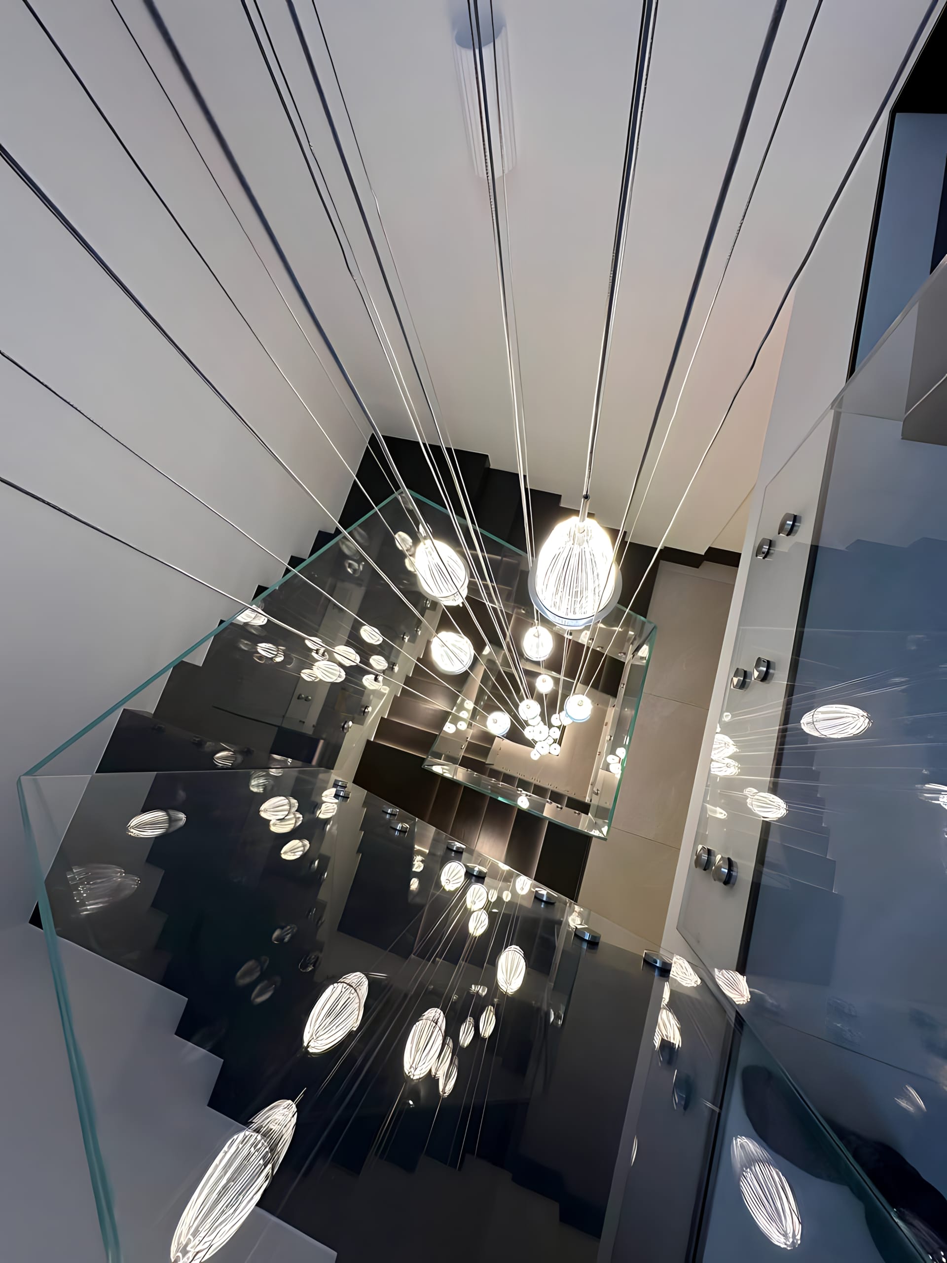 Elegant staircase with glass panel balustrades and sophisticated black wooden stairs, blending transparency with dark allure.