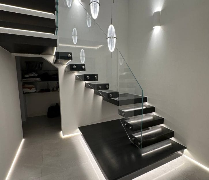 Discover V.P Stairs Ltd's elegant design featuring black wooden stairs paired with glass panel balustrades for a striking modern look.