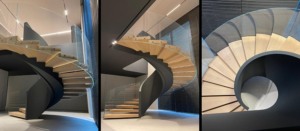 Helical staircase with cherry wood steps, Triplex glass balustrade, and a concrete base by V.P Stairs.