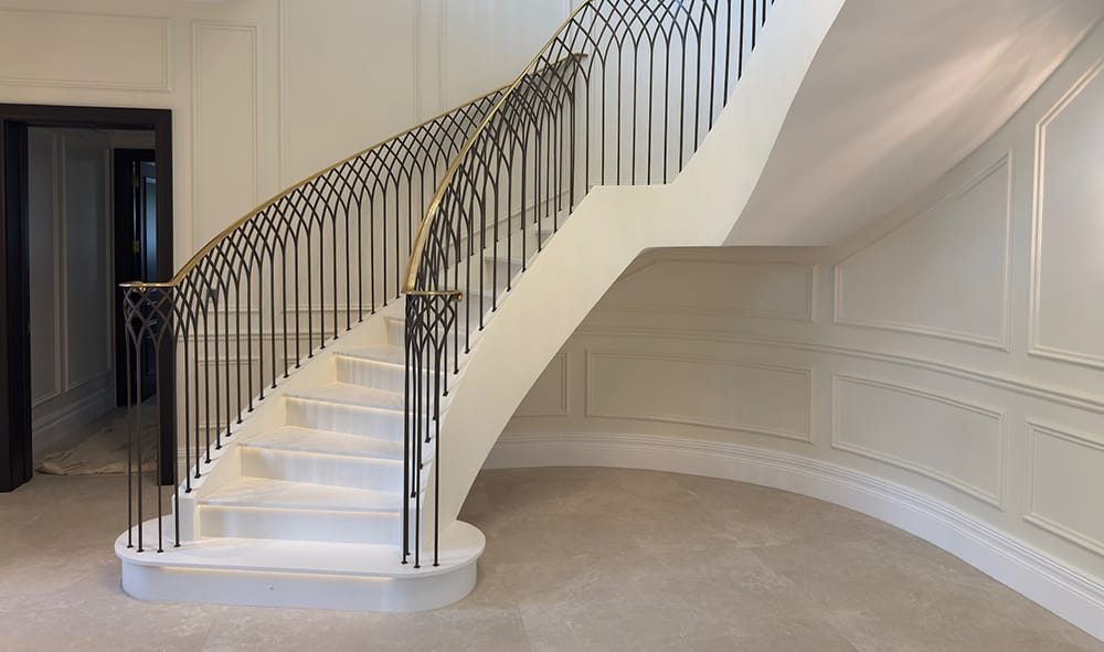 floating curved staircase with brass handrail and gallery balustrade
