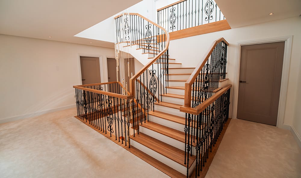 Custom helical and zig-zag staircase with premium oak treads and handcrafted iron balustrades for a luxury UK home