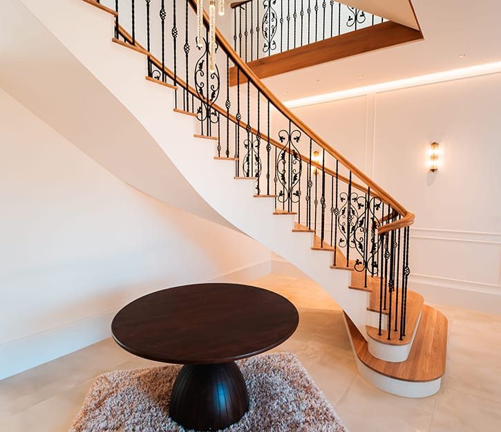 Modern luxury staircase featuring helical and zig-zag flights with solid oak treads and custom forged iron railings in the UK