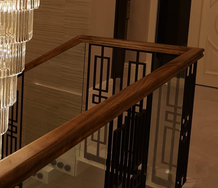 Solid walnut handrail on a bespoke metal and glass staircase balustrade in London