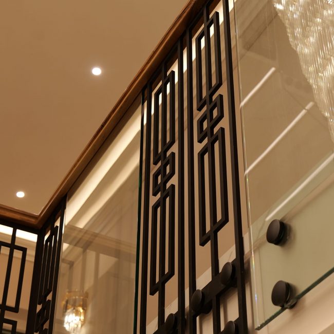 Custom geometric metal and glass balustrade with walnut handrail by V.PSTAIRS