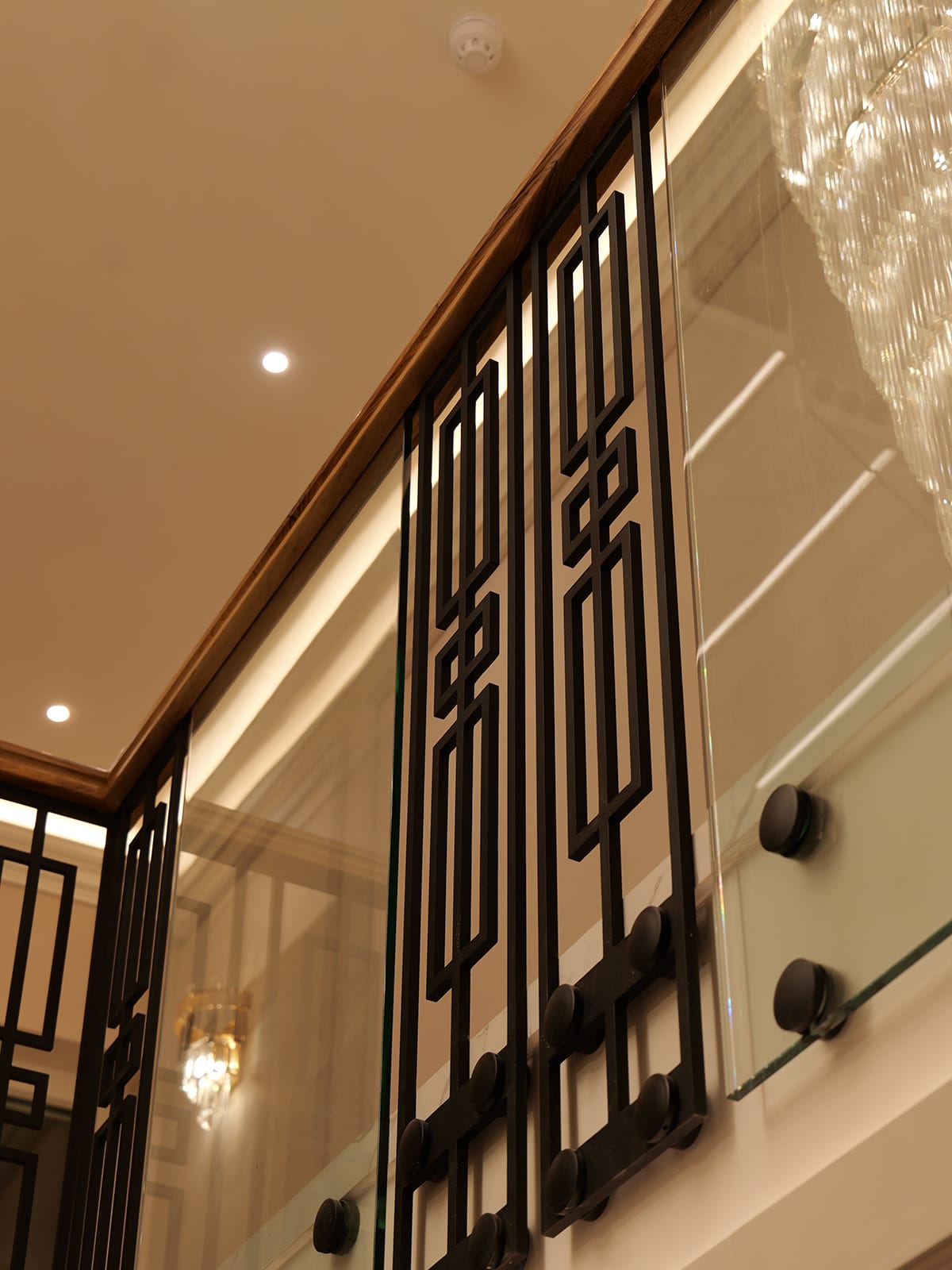 Custom geometric metal and glass balustrade with walnut handrail by V.PSTAIRS